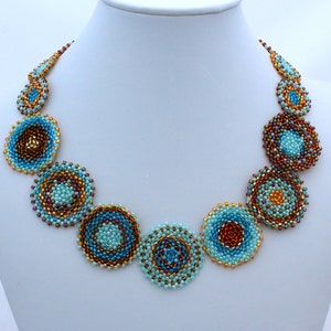 May include: A turquoise and brown beaded necklace featuring circular patterned beads. The necklace is crafted from small beads arranged in a circular pattern, creating a distinctive and eye-catching design.