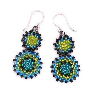 May include: A pair of dangle earrings with two beaded circles in shades of green, blue, and black. The earrings have silver hooks.