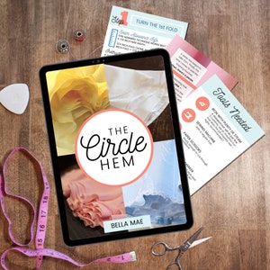 May include: A digital tablet displaying a tutorial for a circle hem sewing technique. The tutorial is titled "The Circle Hem" and features a close-up of a pink fabric with a circle hem. The tablet is on a wooden surface with a pink measuring tape, scissors, and a seam ripper.