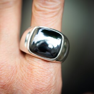 May include: A silver ring with a large, square, black gemstone.