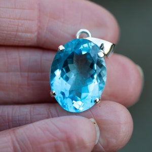 Pu&ograve; includere: Un ciondolo d'argento con una grande pietra preziosa ovale di colore blu chiaro.