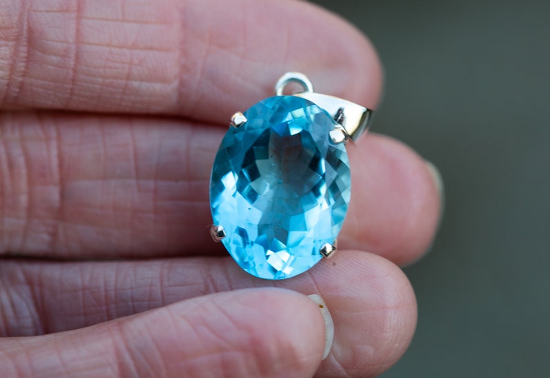 Pu&ograve; includere: Un ciondolo d'argento con una grande pietra preziosa ovale di colore blu chiaro.