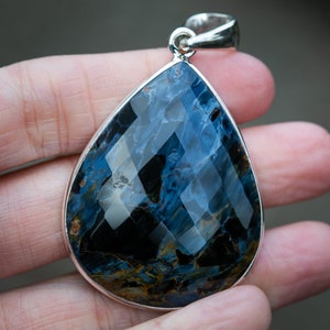May include: A teardrop-shaped pendant with a blue and gold tiger's eye gemstone set in sterling silver.