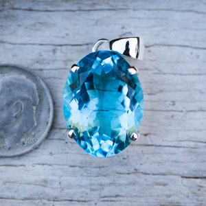 Pu&ograve; includere: Un ciondolo di pietra preziosa di forma ovale, di colore blu chiaro, incastonato in argento. Il ciondolo &egrave; circa delle dimensioni di una moneta da dieci centesimi di euro.