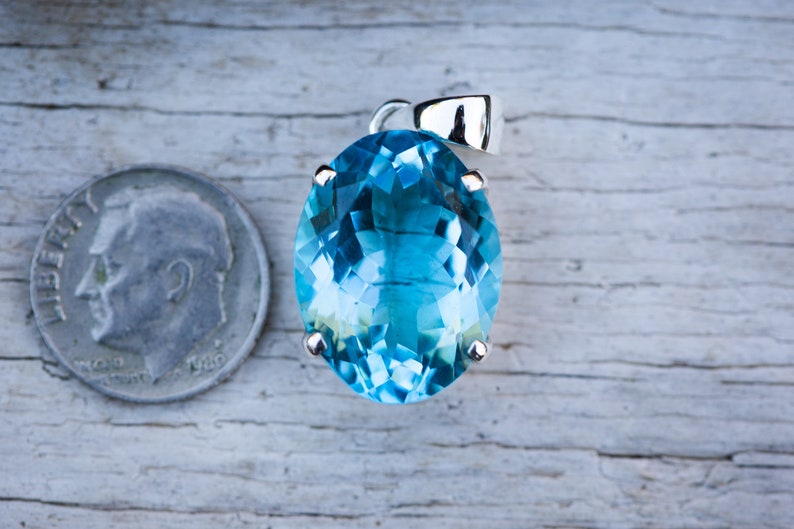 Pu&ograve; includere: Un ciondolo di pietra preziosa di forma ovale, di colore blu chiaro, incastonato in argento. Il ciondolo &egrave; circa delle dimensioni di una moneta da dieci centesimi di euro.
