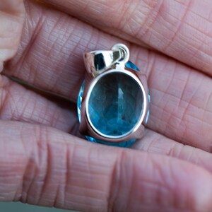 Pu&ograve; includere: Un ciondolo d'argento con una grande pietra preziosa rotonda di colore blu chiaro. Il ciondolo ha un design semplice ed elegante.