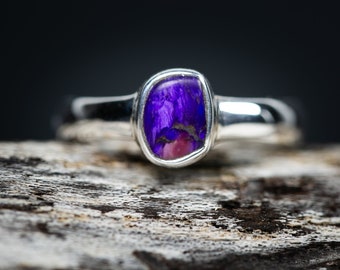 May include: A silver ring with a purple and pink gemstone set in a bezel setting.