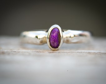 May include: A silver ring with a purple gemstone set in the center.