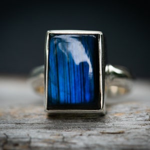 May include: A silver ring with a rectangular blue labradorite gemstone.