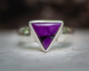 Puede incluir: Un anillo de plata con una piedra preciosa de color púrpura triangular.