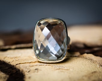 May include: A silver ring with a large, clear, faceted gemstone.