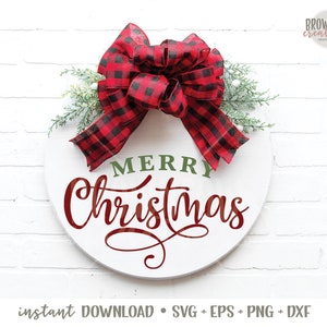 May include: A white round wooden sign with the words "Merry Christmas" in red cursive lettering and "Merry" in green lettering. A red and black buffalo plaid bow with green sprigs is attached to the top of the sign.