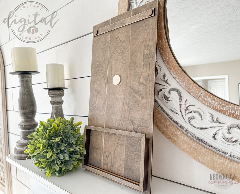 May include: A wooden wall shelf with a built-in phone stand. The shelf is stained a dark brown color and has a rustic look. The phone stand is made of the same wood and is attached to the bottom of the shelf. The shelf is mounted on a white wall.