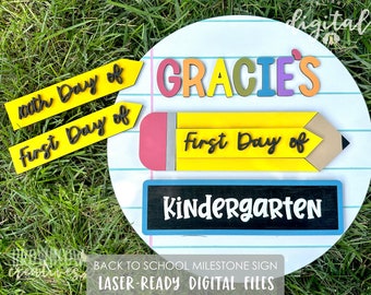 May include: A yellow pencil with the words "First Day of" on it, a blue sign with the word "Kindergarten" on it, and a yellow sign with the words "100th Day of" on it. There is also a sign with the name "GRACIES" on it, with each letter in a different color. The signs are on a white background with blue lines.