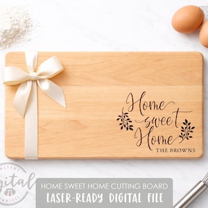 May include: A rectangular wooden cutting board with the words "Home sweet Home" engraved on it. A cream-colored ribbon and bow are tied to the side. The text "THE BROWNS" is below the main text. Two eggs are in the background.