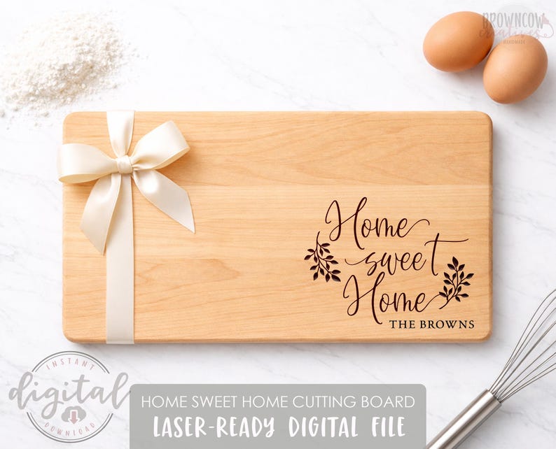 May include: A rectangular wooden cutting board with the words "Home sweet Home" engraved on it. A cream-colored ribbon and bow are tied to the side. The text "THE BROWNS" is below the main text. Two eggs are in the background.