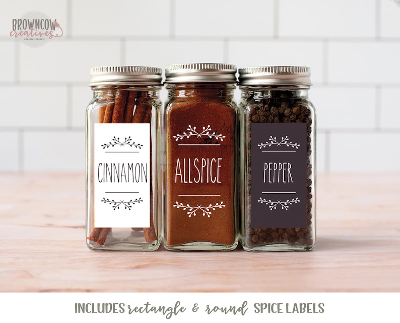 May include: Three glass spice jars with labels that say "Cinnamon", "Allspice", and "Pepper". The labels have a simple floral design and black text. The jars are filled with spices.