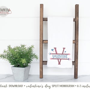 May include: White Valentine's Day split monogram towel with a brown wooden ladder. The towel features a large letter "V" with the word "VALENTINE" and arrow accents in pink and blue. A small potted plant is on the left.