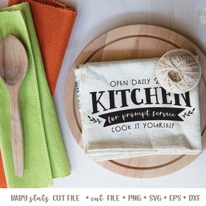 K&ouml;nnte beinhalten: Ein wei&szlig;es K&uuml;chentuch mit schwarzem Text, der "Open Daily 2 Kitchen for prompt service. Cook it yourself." lautet. Das Tuch wird auf einem Holzbrett mit einer Schnurkugel pr&auml;sentiert.