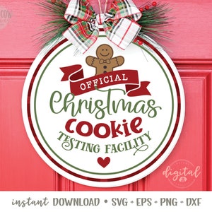 May include: A white round sign with green and red accents. The sign says "Official Christmas Cookie Testing Facility" with a gingerbread man graphic and a red ribbon.