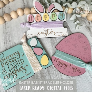 May include: Three laser-cut wooden Easter bracelet holders. One is pink with a bunny design and the text "Happy Easter". Another is teal with the text "Bunny Kisses & Easter Wishes". The third is white with the text "Hoppy Easter".