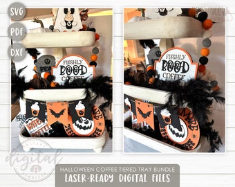 May include: A tiered tray decorated for Halloween with orange, black and white accents. The tray features a sign that says "Fleshly Pood Coffee", a banner with a bat and coffee cups, and a round sign with a pumpkin face.