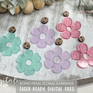 Könnte beinhalten: Lasergeschnittene Blumenohrringe in Pink, Lila und Grün. Die Ohrringe sind blumenförmig mit einem Loch in der Mitte. Die Ohrringe werden auf einer weißen Holzoberfläche mit Holzknöpfen gezeigt.
