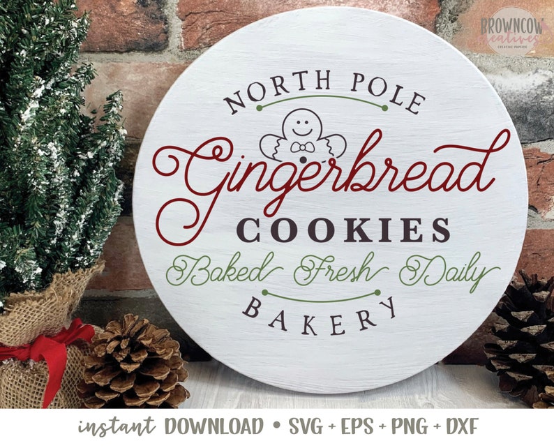 May include: A white round sign with the text "North Pole Gingerbread Cookies Baked Fresh Daily Bakery" in red, green, and black lettering. A gingerbread man cookie illustration is in the center of the sign.