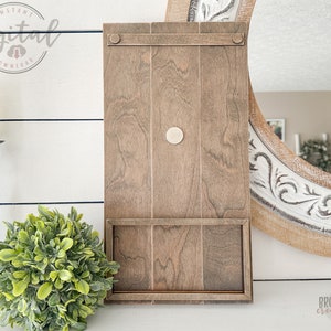 May include: A wooden wall shelf with a single shelf and a small, round, white knob. The shelf is stained a dark brown color and has a rustic look.