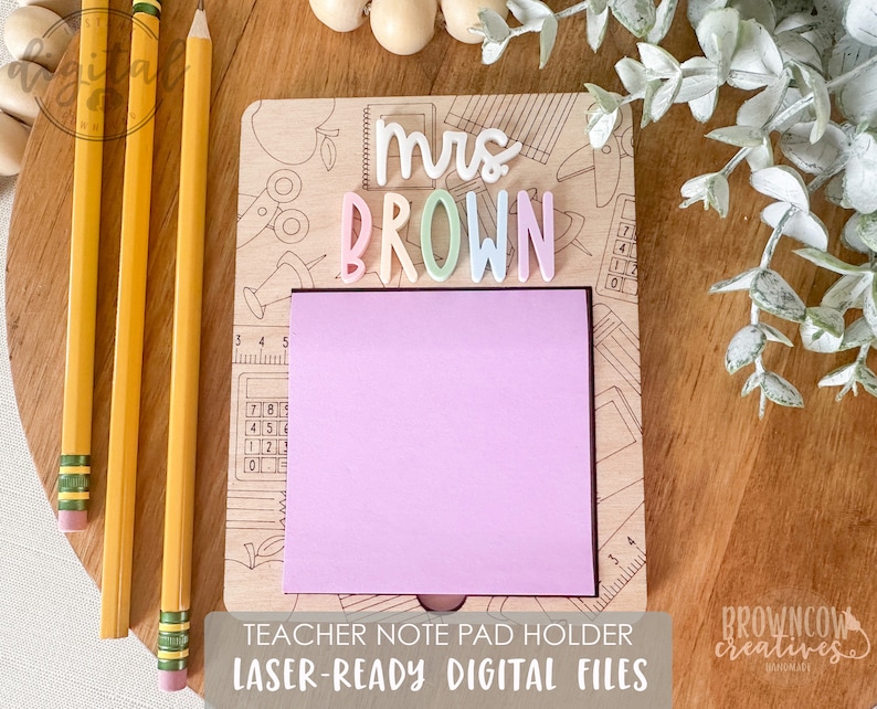 May include: A wooden note pad holder with a pink sticky note and the text "Mrs. BROWN" in colorful letters. The holder is designed for teachers and includes a ruler and calculator graphic.