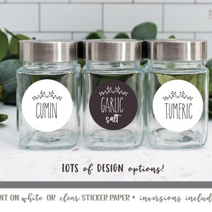 May include: Three glass spice jars with silver lids and round white labels with black text and simple floral designs. The labels read "Cumin", "Garlic Salt", and "Tumeric".
