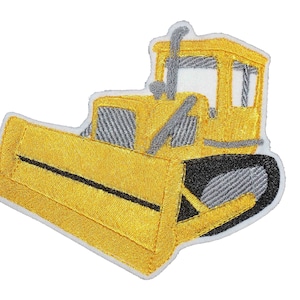 Pode incluir: Etiqueta bordada amarela de um bulldozer com uma faixa preta na lâmina.