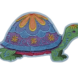 May include: A colourful embroidered patch of a turtle with a flower design on its shell. The turtle is green with a purple, blue and orange shell.