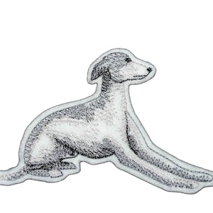 May include: Black and white embroidered patch of a dog lying down. The dog is facing to the right and has its head turned to the left. The dog's tail is curled up behind it.