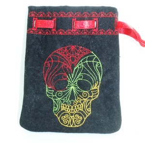 Pode incluir: Saco de cordão de veludo preto com um design de caveira bordado em vermelho, verde e amarelo. A caveira tem detalhes intrincados e um padrão floral.