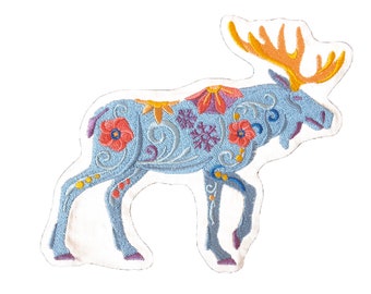 May include: A blue embroidered moose with floral and snowflake designs. The moose is standing on a white background.