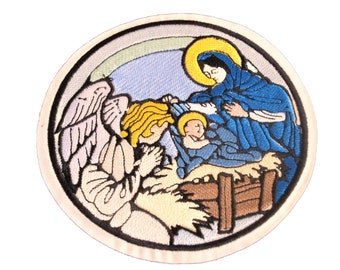 May include: Embroidered patch depicting the Nativity scene with a haloed angel, Mary, and baby Jesus in a manger. The angel has wings and is kneeling in prayer. Mary is wearing a blue robe and is holding the baby Jesus. The manger is made of wood and straw.