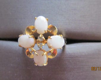 May include: A gold ring with five white oval-shaped stones set in a floral design.