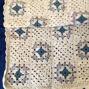 Baby afghan, hand crocheted granny squares using off white, a variegated, blue center, shell edging, length is 33 inches width 32 inches