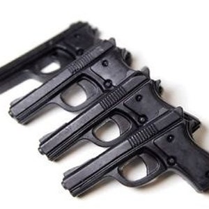 May include: Three black plastic toy guns, arranged in a row, with the barrels pointing to the right.