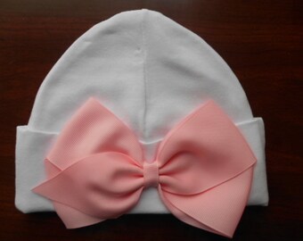 Sombrero de bebé suave hecho de algodón.  Este sombrero tiene un elegante lazo de cinta rosa claro. El sombrero se adapta a los bebés desde el nacimiento hasta aproximadamente los 3 meses.