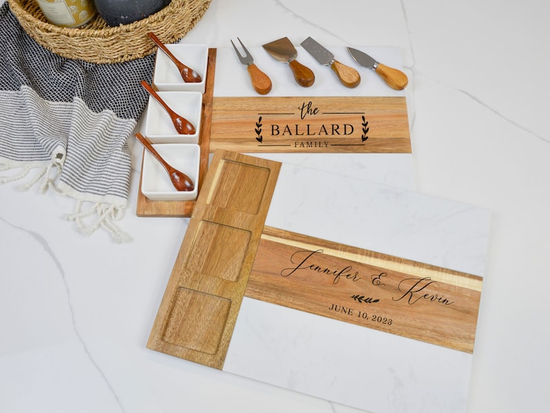 May include: Two wooden serving boards with a marble design. The smaller board has three small bowls and the text "the BALLARD FAMILY". The larger board has the text "Jennifer & Kevin JUNE 10, 2023".