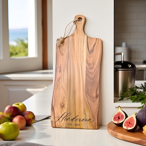 A Personalized cutting board with the couples in script font and the date engraved, placed against a modern kitchen backdrop.