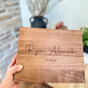 May include: A wooden box with a hinged lid, engraved with the names "Ryan Allanah" and the date "02.18.24".