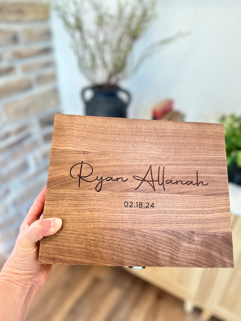 May include: A wooden box with a hinged lid, engraved with the names "Ryan Allanah" and the date "02.18.24".