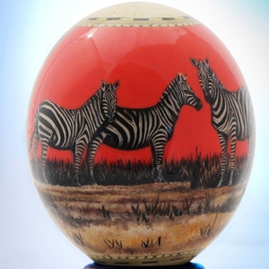Decoupage red ostrich egg: African animals such as zebra, lion or rhino are portrayed against a rich red sky with a map on the reverse side