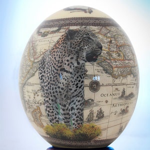 Decoupage Leopard Straußenei: Ein einzelner Leopard sticht seine Beute mit einer detaillierten Weltkarte auf der Rückseite des Straußeneis