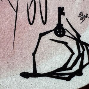 May include: Black and white line drawing of a hand holding a key. The hand is stylized and appears to be reaching out.