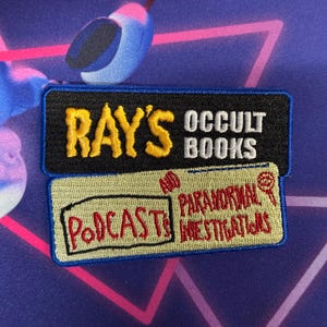 Pode incluir: Um remendo bordado azul e preto com o texto "Ray's Occult Books and Paranormal Investigations" e as palavras "Podcasts" em vermelho.