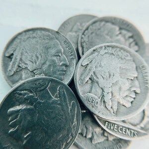 K&ouml;nnte beinhalten: Nahaufnahme eines Stapels silberfarbener US-F&uuml;nf-Cent-M&uuml;nzen mit dem Profil eines amerikanischen Indianers. Die M&uuml;nzen sind mit 1930 datiert und tragen die Inschriften "Liberty" und "Five Cents".